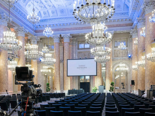Inside view of the Zeremoniensaal at Hofburg in Vienna with a screen, chairs in rows and chandeliers